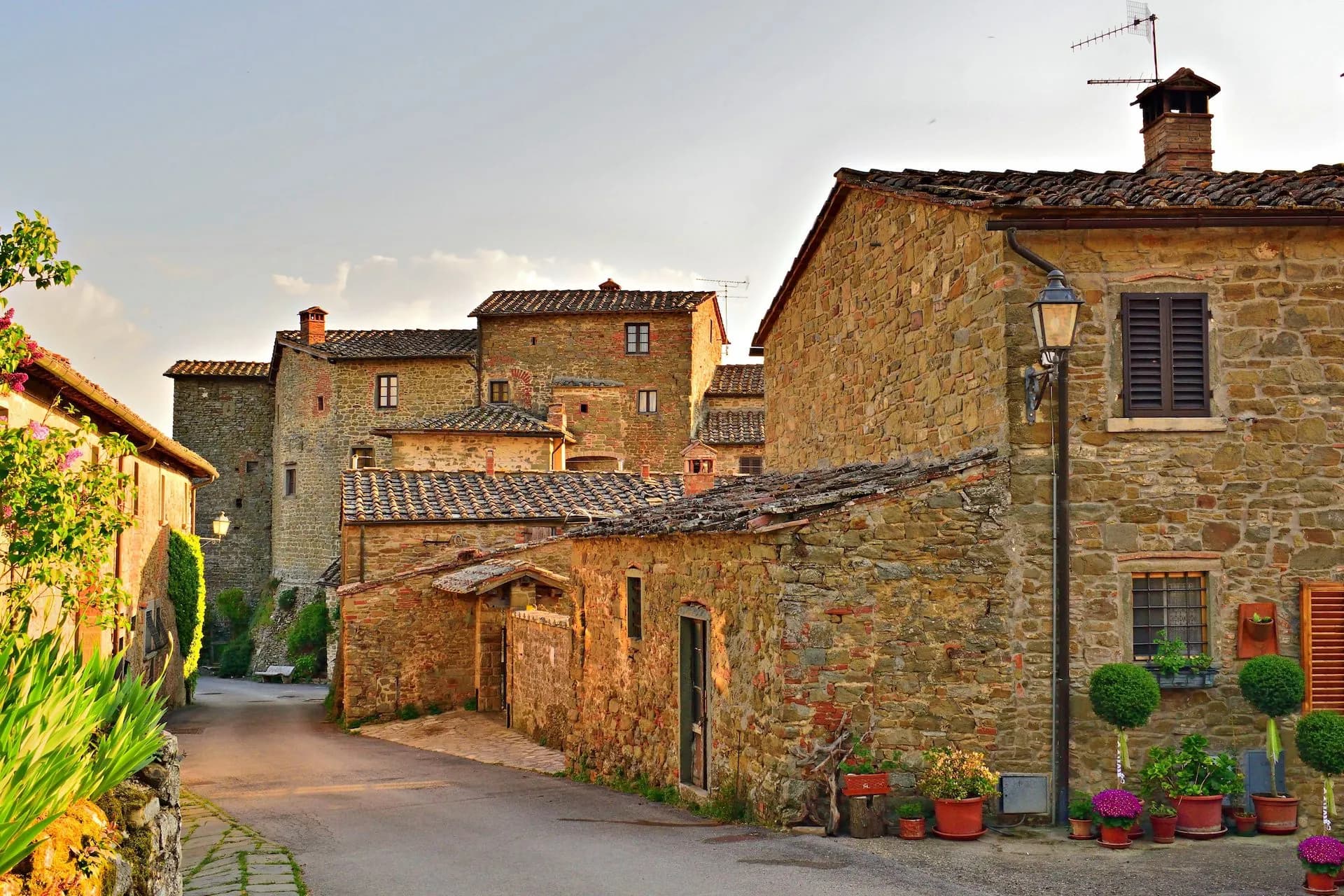 Stone buildings with terracotta roofs line a quiet, sunlit street in Radda in Chianti.