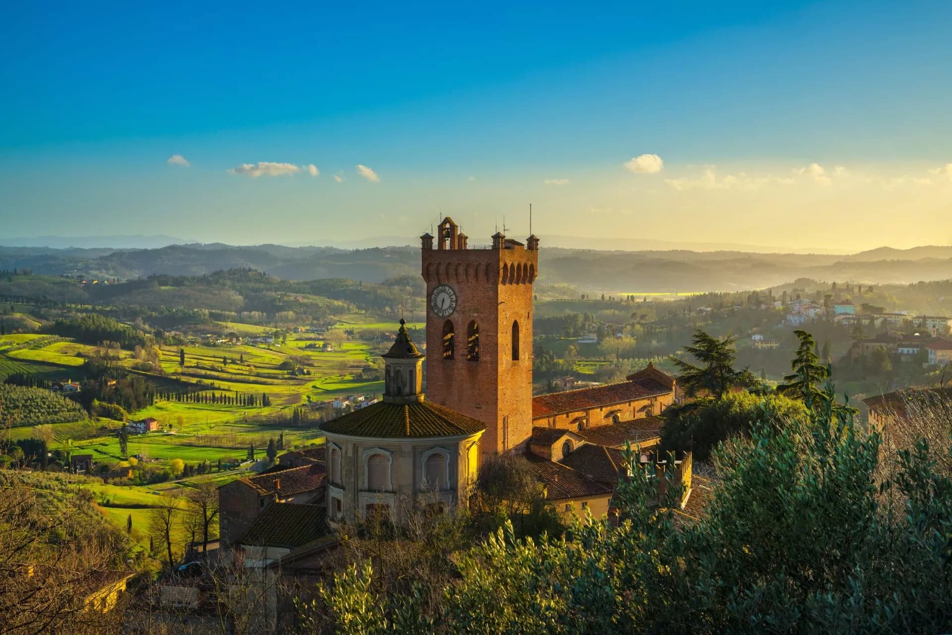 San Miniato bell tower overlooking rolling green Tuscan hills at sunset