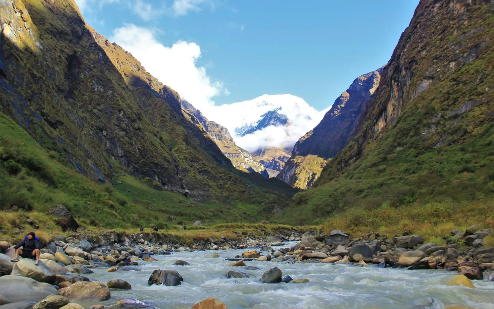 Trekking near Annapurna Base Camp with a fast-flowing river and snow-capped mountain peaks.
