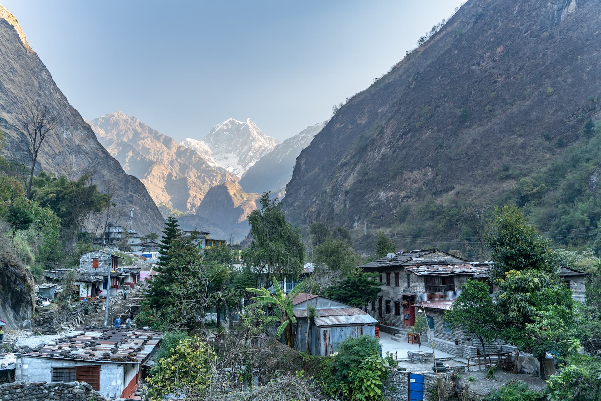 Tatopani village nestled in a deep valley with snow-capped Himalayan peaks in the background.