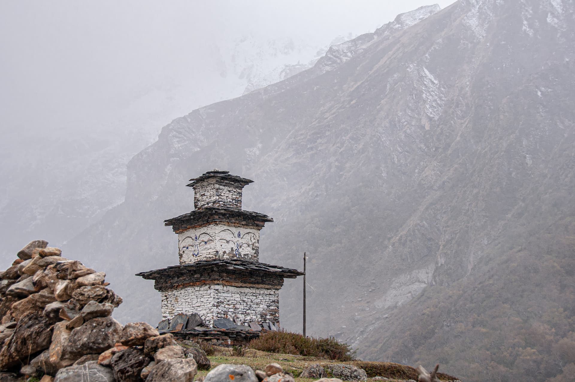 Buddhist Chorten in Samdo village against foggy, snow-dusted mountain slopes.