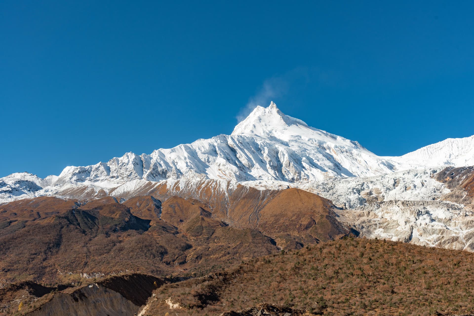 Snow-capped Mount Manaslu towering over brown foothills seen on the way to Samdo.