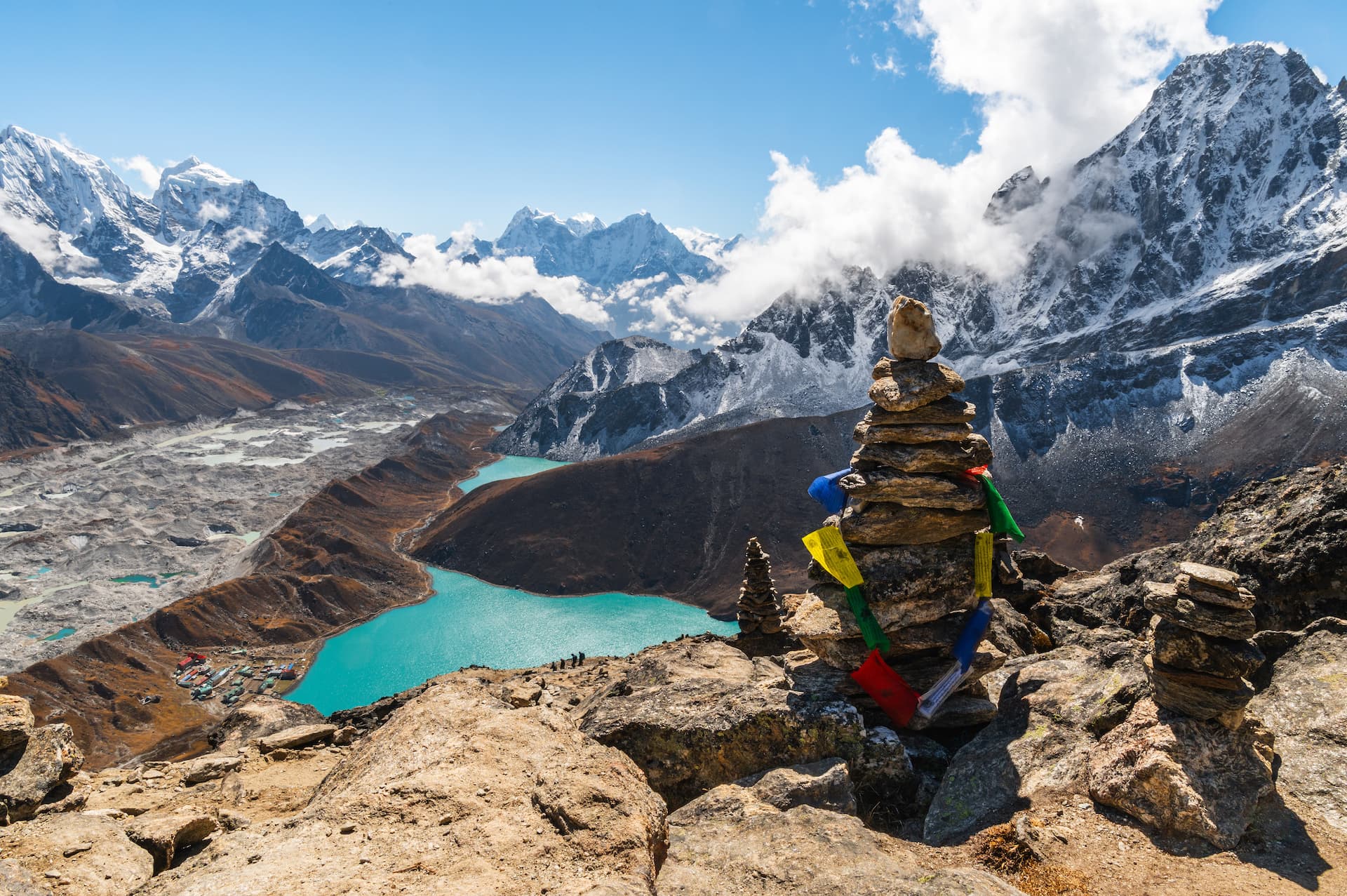 Stone cairn with prayer flags overlooking Gokyo Lakes and Himalayan peaks.