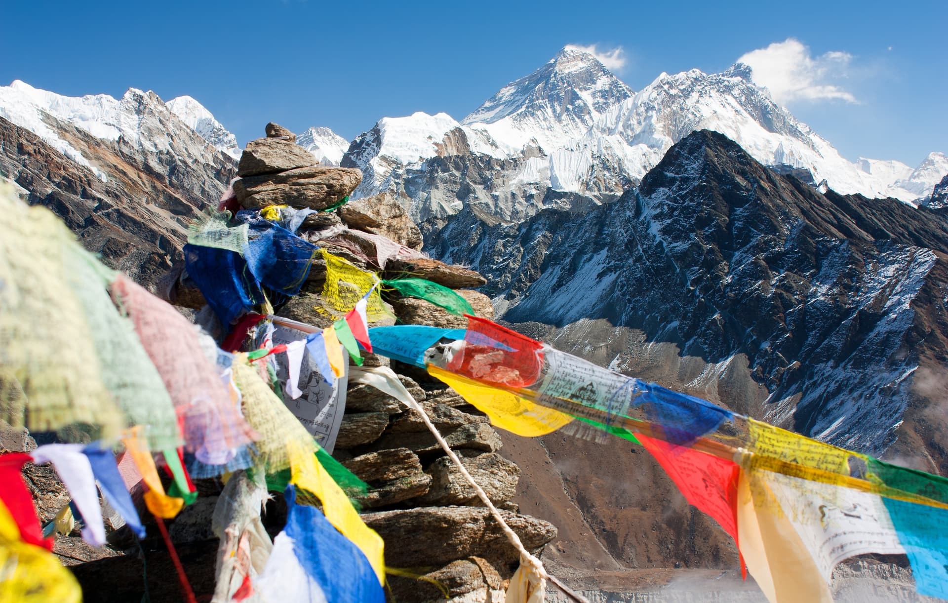 Prayer flags blowing in wind near cairn with view of Mount Everest from Gokyo Ri.