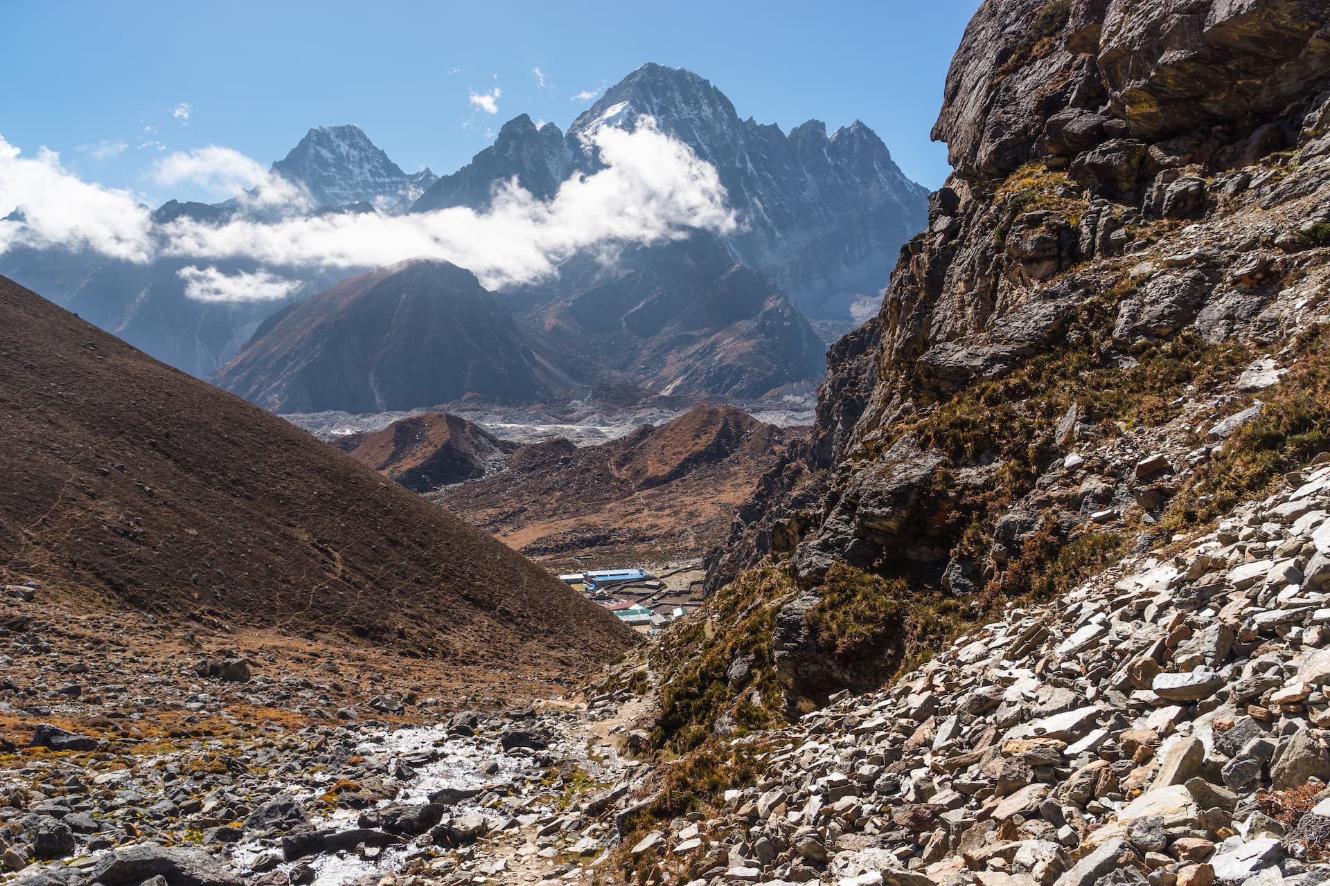 View of Tagnag village nestled in a rocky valley below snow-capped Himalayan peaks.
