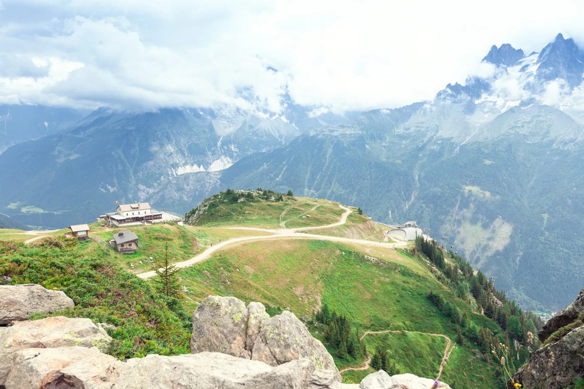 Mountain refuge and trails on a green alpine ridge above Chamonix valley.
