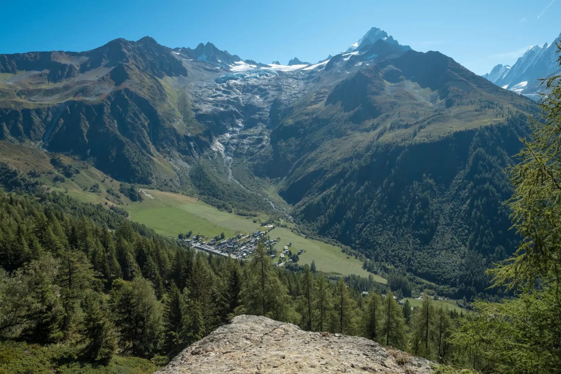 View of Le Tour village nestled in an alpine valley below a glacier and snow-capped mountains.
