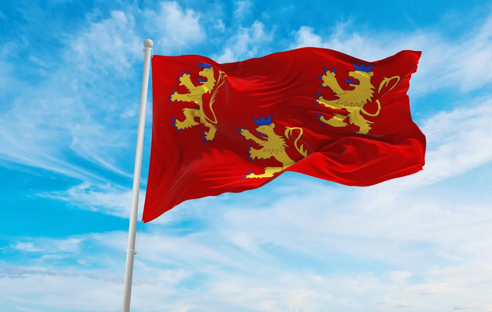 Flag of the Department of Dordogne waving on a flagpole against a blue, cloudy sky.