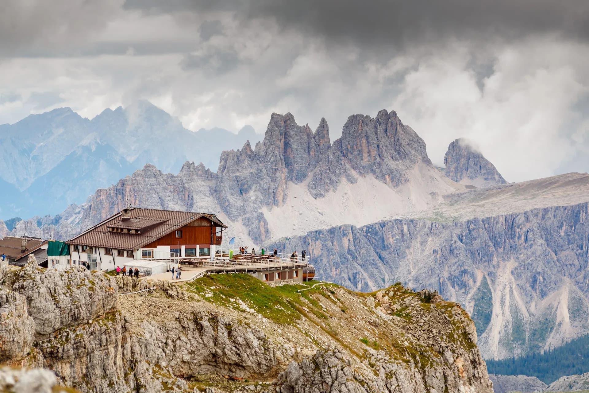 Rifugio Lagazuoi mountain hut on rocky ridge with dramatic Dolomite peaks under cloudy sky.