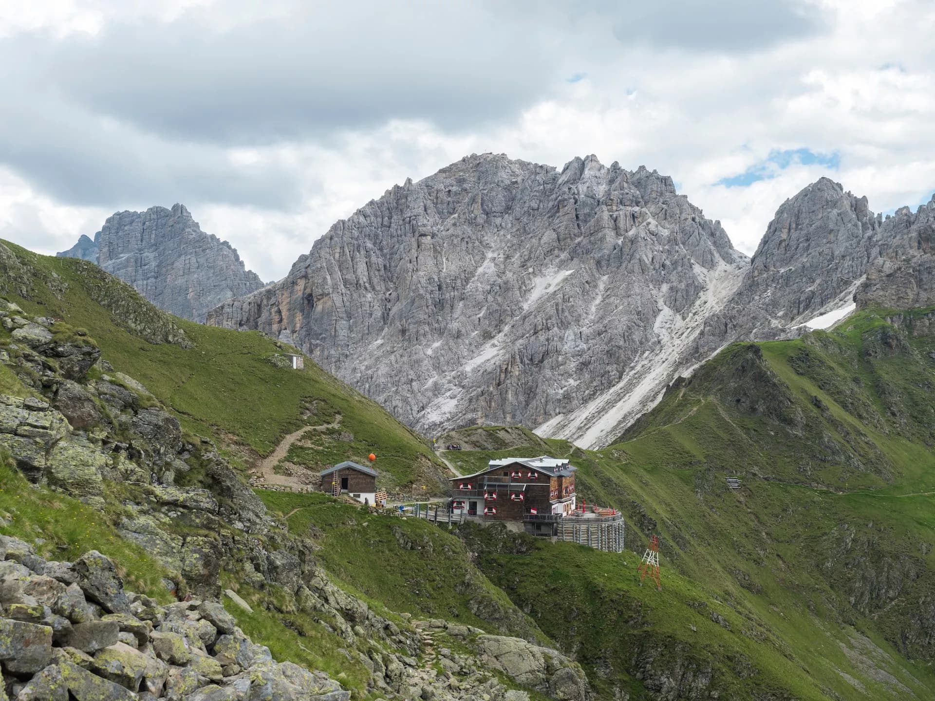 Innsbrucker Hutte mountain refuge nestled in green alpine slopes below jagged gray peaks.
