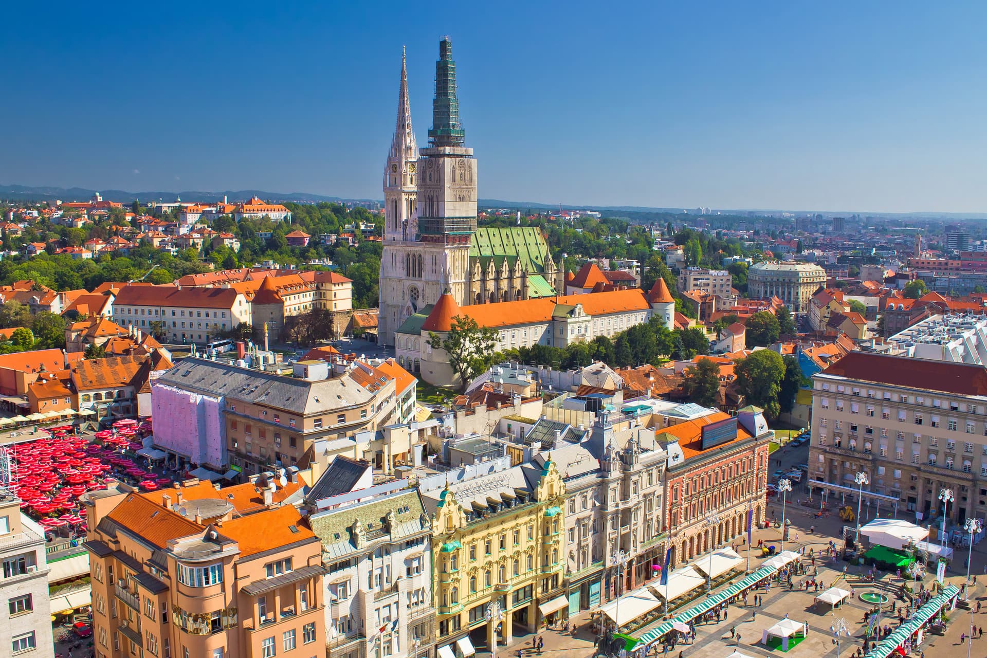 Aerial view of Zagreb with the Cathedral towers, orange rooftops, and busy city square.
