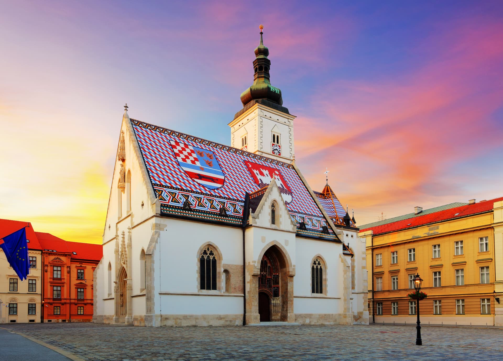 St Mark's Church in Zagreb with colorful tiled roof against a vibrant sunset sky.
