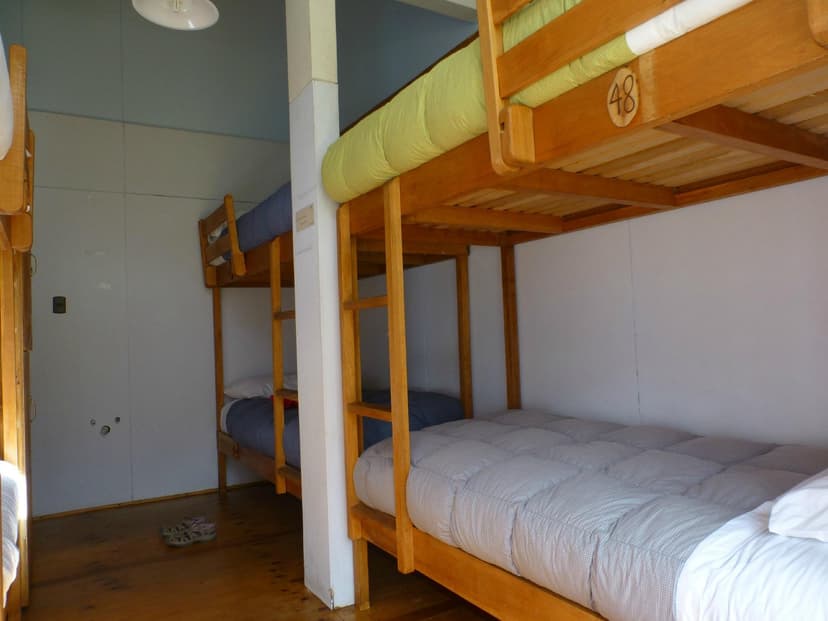 Bunk beds with wooden frames and mattresses inside a simple room, possibly a refuge.
