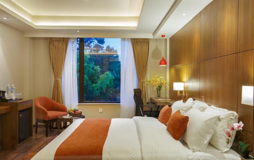 Hotel Thrive Kathmandu room with white bedding, wood paneling, and a large window view of green trees.