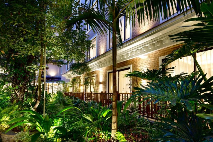 Hotel Thrive Kathmandu exterior at night with lush, illuminated tropical garden and brick building.