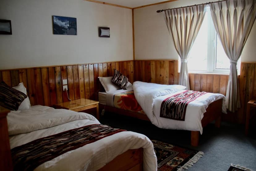 Twin bedroom in Panorama Lodge Namche Bazaar with wood paneling and mountain art.