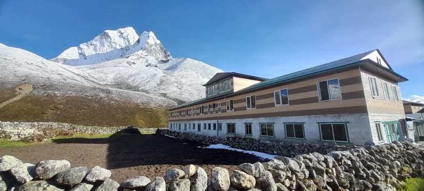 Hotel building in Dingboche with snow-capped mountain under bright blue sky