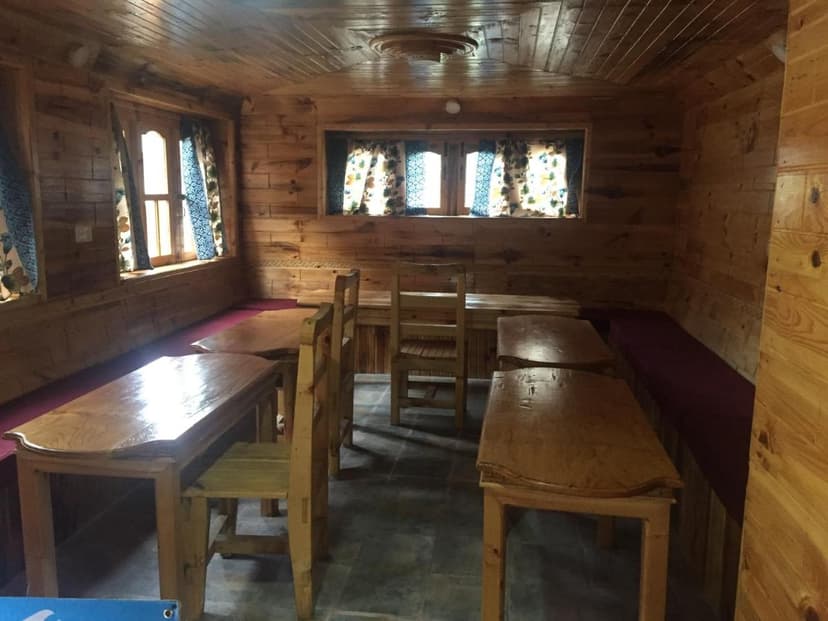 Wooden lodge dining room interior with simple wooden tables, chairs, and bench seating in Phakding.