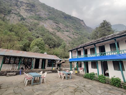 Green View Lodge with outdoor seating nestled against a steep, forested mountain slope.