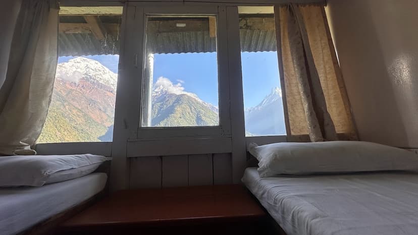 Twin beds in lodge room with view of snow-capped mountains through window