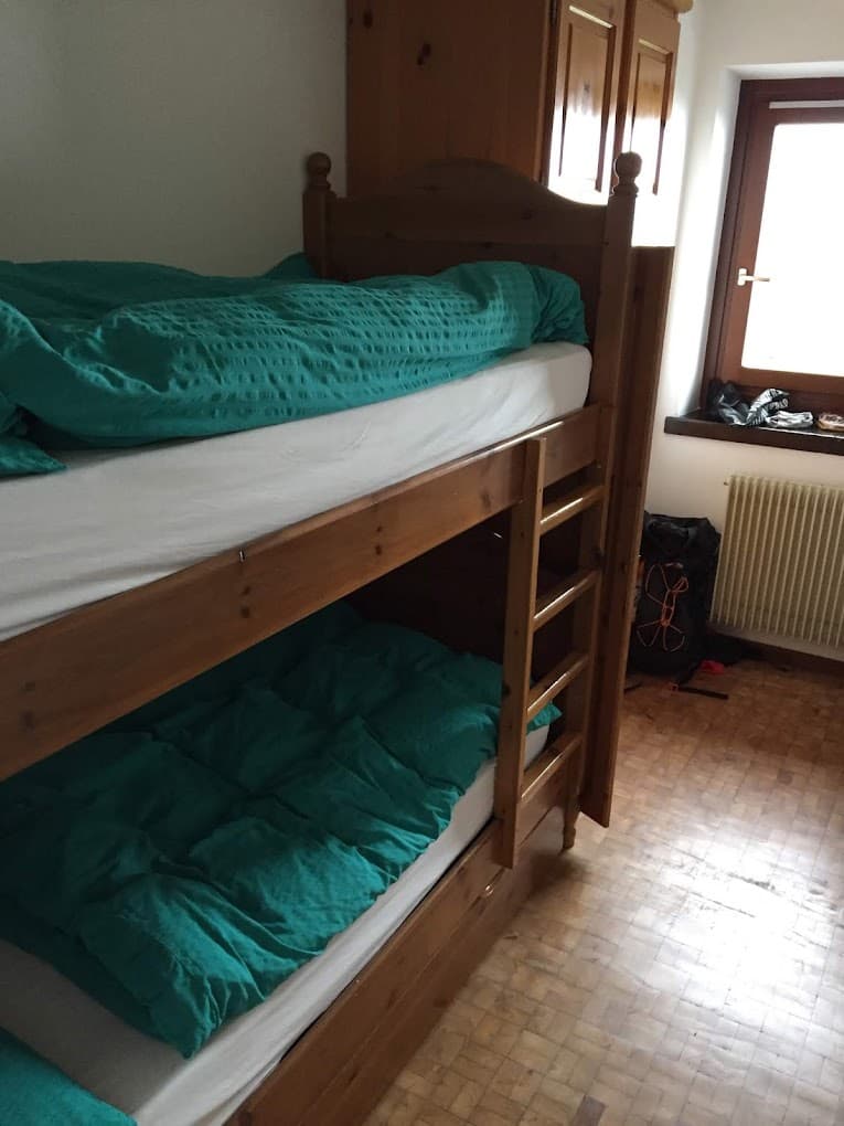 Wooden bunk beds with teal duvets in a room with a window and wooden floor.