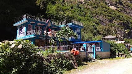 Gorkha Guest House Dharapani building against a steep, green hillside.