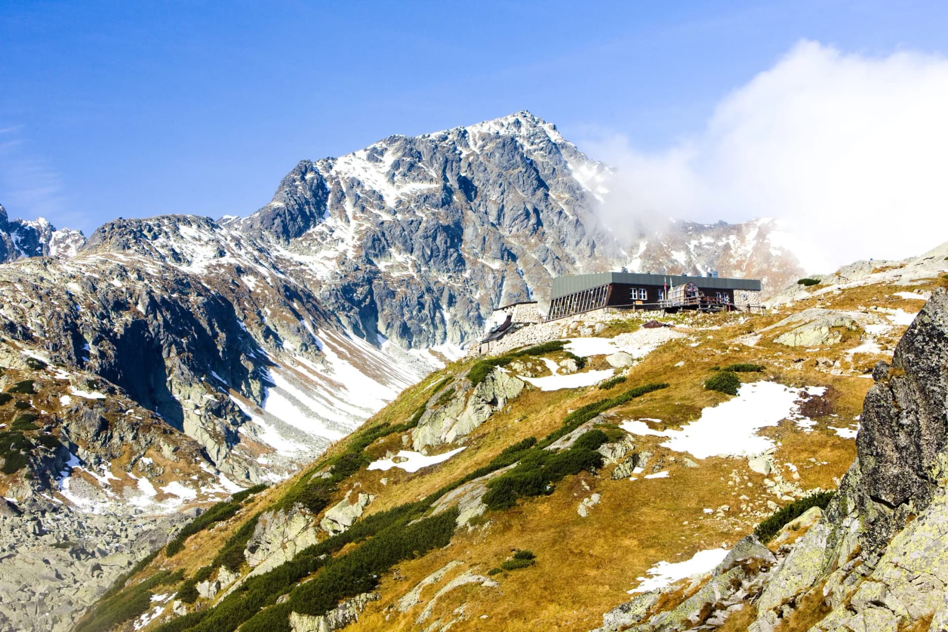 Zbojnícka chata mountain hut nestled in snowy, rocky terrain below a high peak in the Tatras.