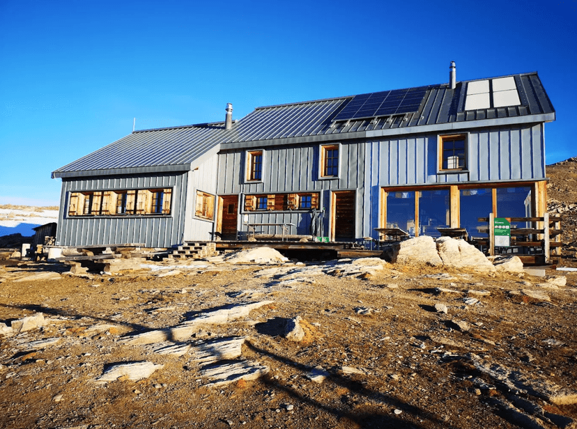 Cabane des Becs-de-Bosson mountain hut with solar panels under a clear blue sky.