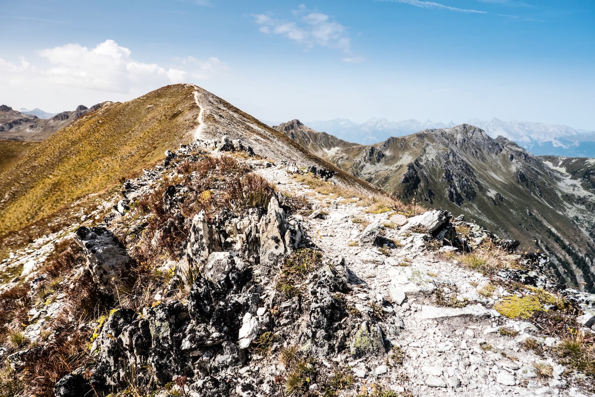 Hiking trail along a rocky mountain ridge toward Roc d’Orzival summit under a blue sky.