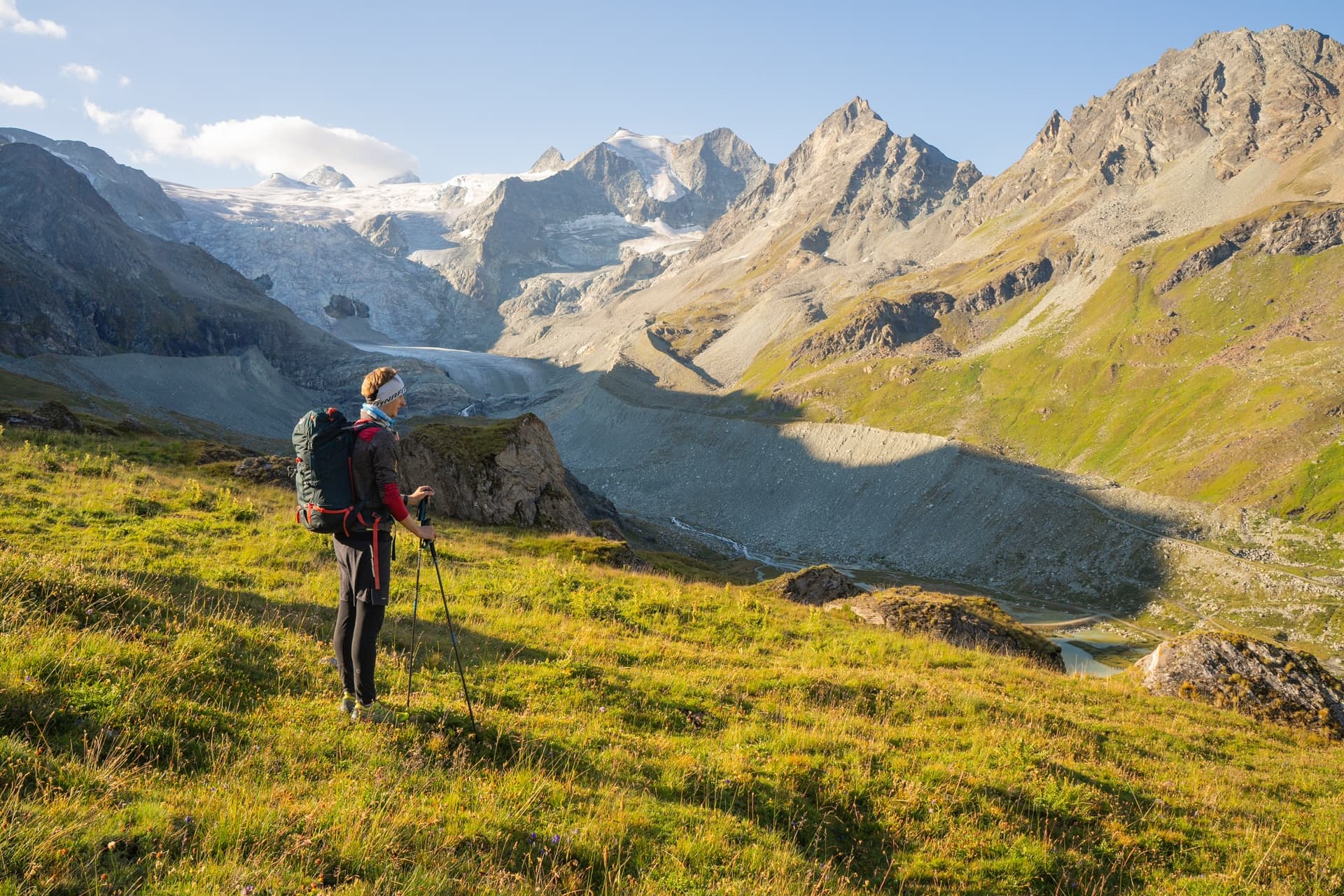 Hiker with backpack and poles overlooking glacier and rugged mountains at Lac de Moiry.