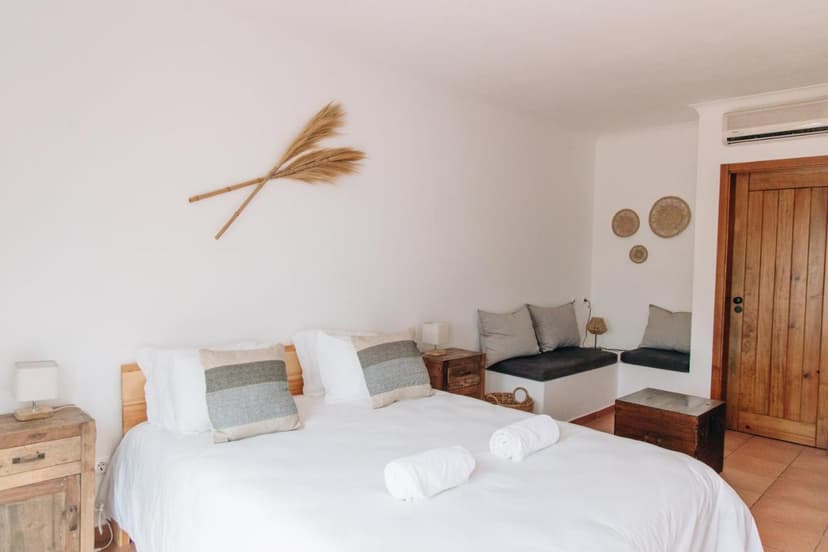 Bright bedroom with white walls, wooden bed, and natural fiber wall decor.