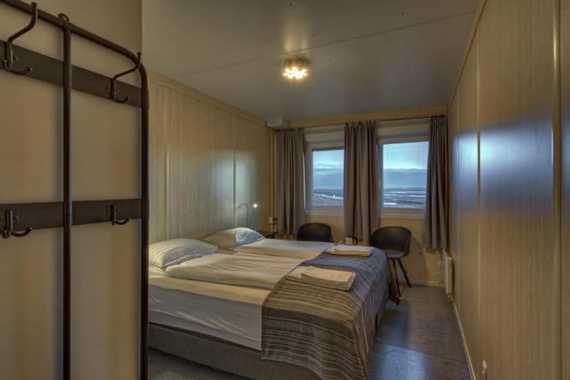 Twin beds in a simple room with wood paneling and view of coastal flats.