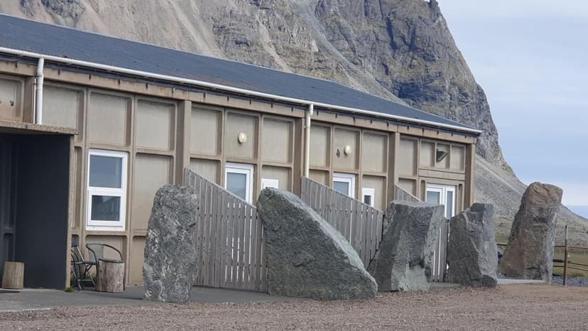 Low-rise building with concrete facade, large boulders, and steep mountain backdrop