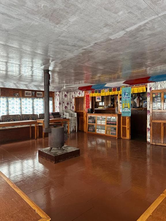 Lodge common area with wood stove, seating, and counter, likely in Phortse Tanga.