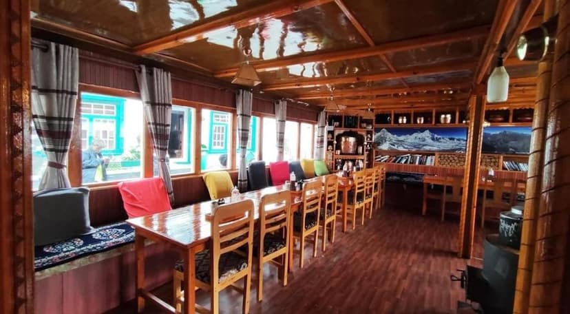 Wooden dining area with colorful cushions and mountain decor in Hotel Sherpa Village Namche Bazaar.