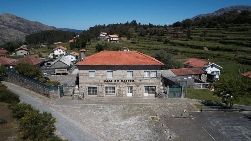 Casa do Destro Guest House with stone facade and red tile roof in a mountainous village setting.