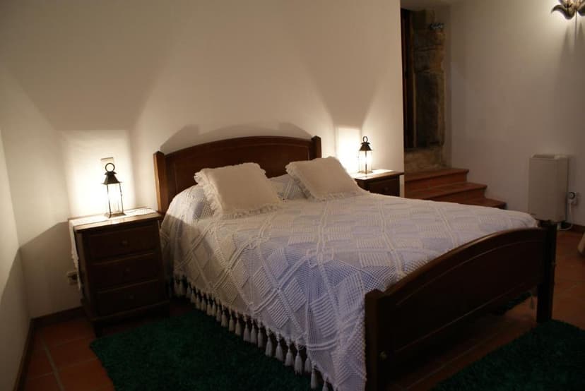 Bedroom with wooden bed, white crocheted blanket, and lantern-style bedside lamps