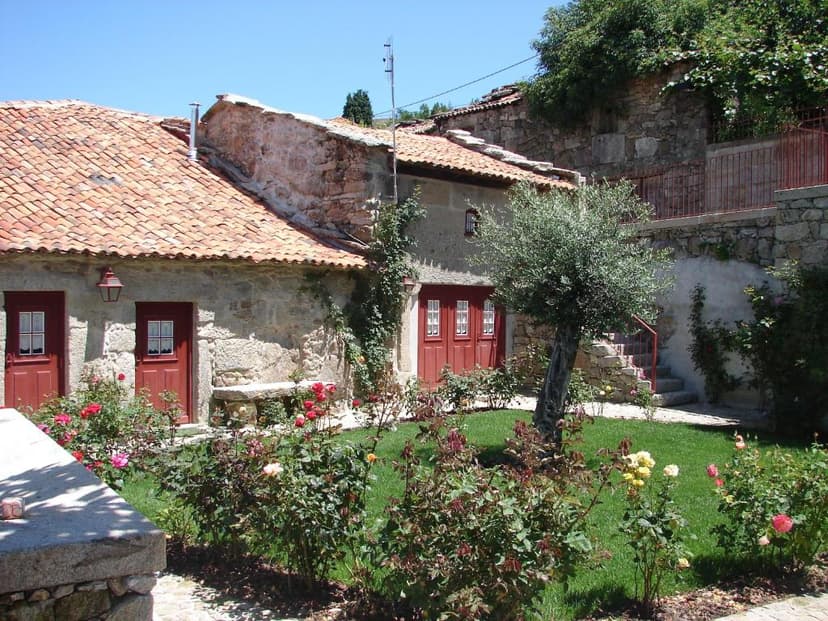 Stone building with terracotta roof and garden roses, Casa Real Danaia setting