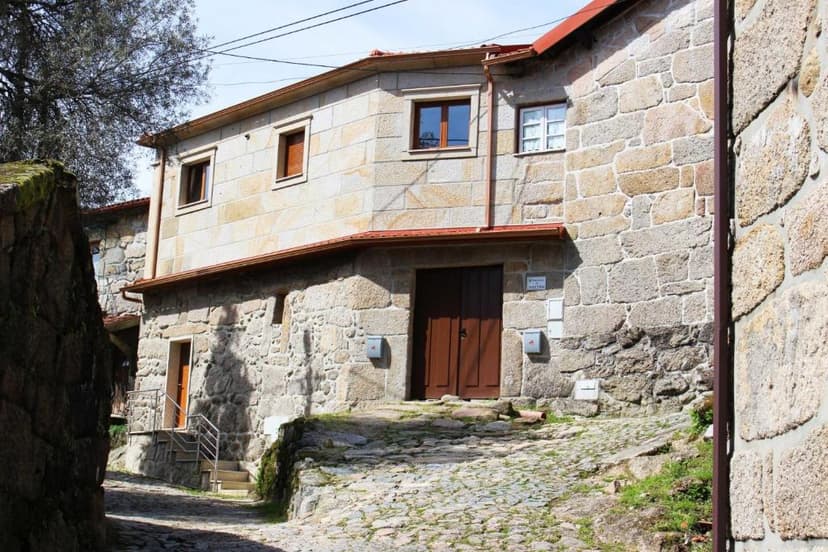 Stone house exterior in Vilar with brown wooden doors and cobblestone street.