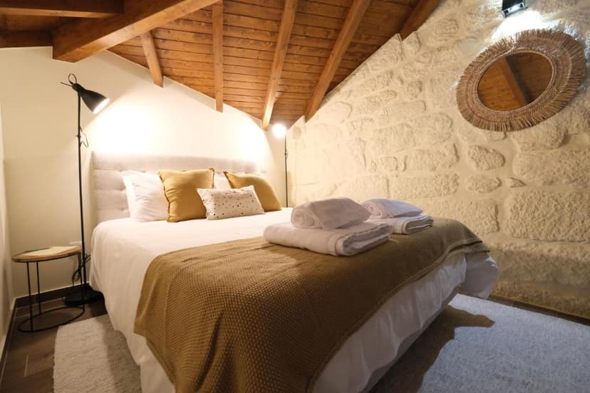 Cozy guest house bedroom with stone wall, wood ceiling, and mustard yellow accents.
