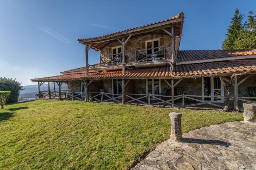Stone hotel with terracotta roof and wooden balconies overlooking a valley vista