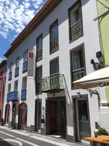 Hotel Alcides building facade on a narrow street with patterned pavement under a sunny sky.