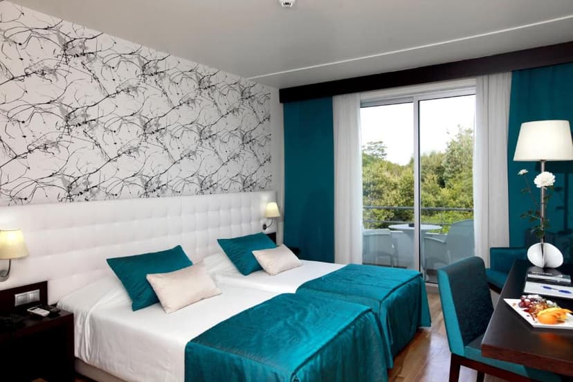 Twin hotel room with teal accents, white headboard, and balcony view of trees, Hotel Vale Do Navio