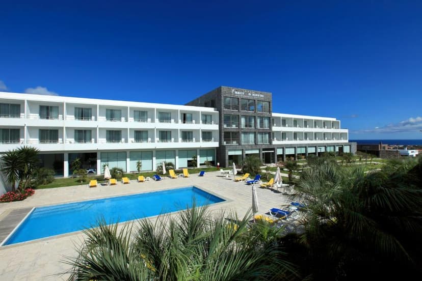 Hotel Vale do Navio with outdoor pool, sun loungers, and palm trees under a clear blue sky.