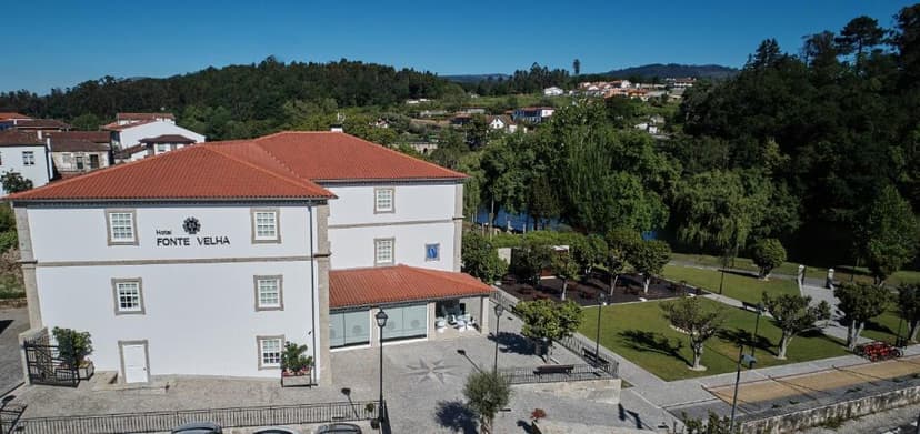 Hotel Fonte Velha building with white walls and red tile roof, set against green hills.