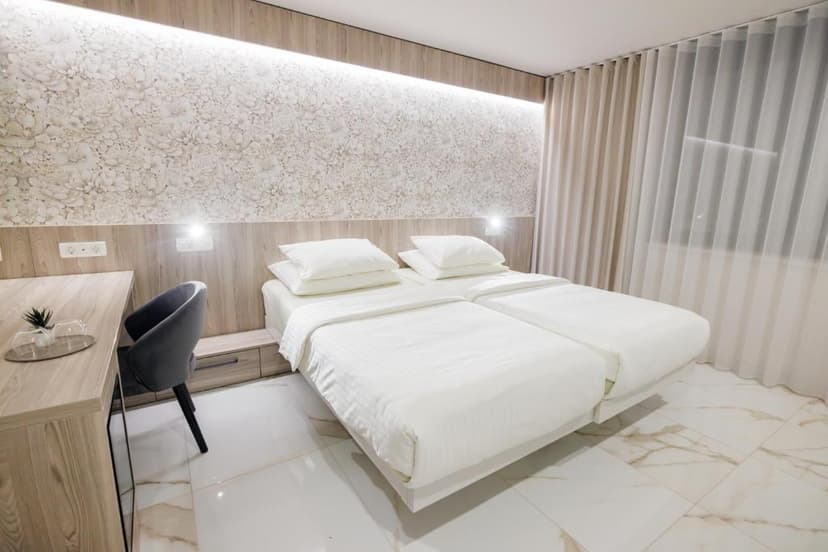 Twin beds with white linens in a modern hotel room at Hotel Capris Capodistria.