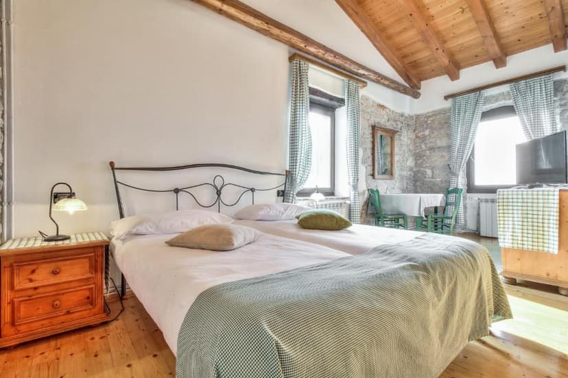 Bedroom with twin beds, wood ceiling beams, and stone accent wall, Casa Romantica La Parenzana