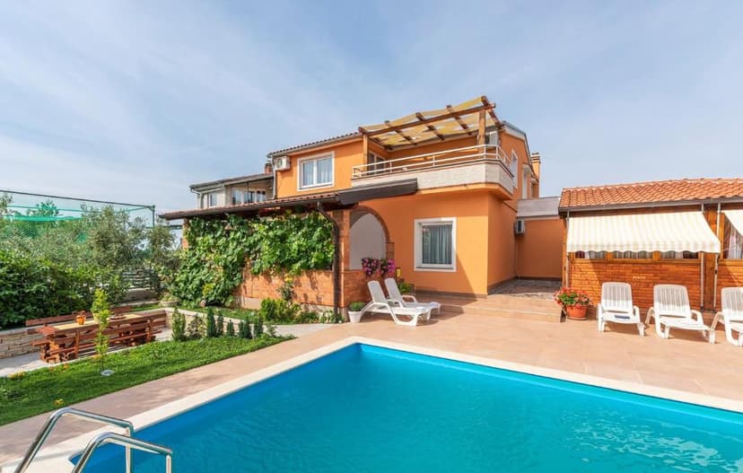 Orange villa with pool, lounge chairs, and outdoor dining area in Villa Višnjan.