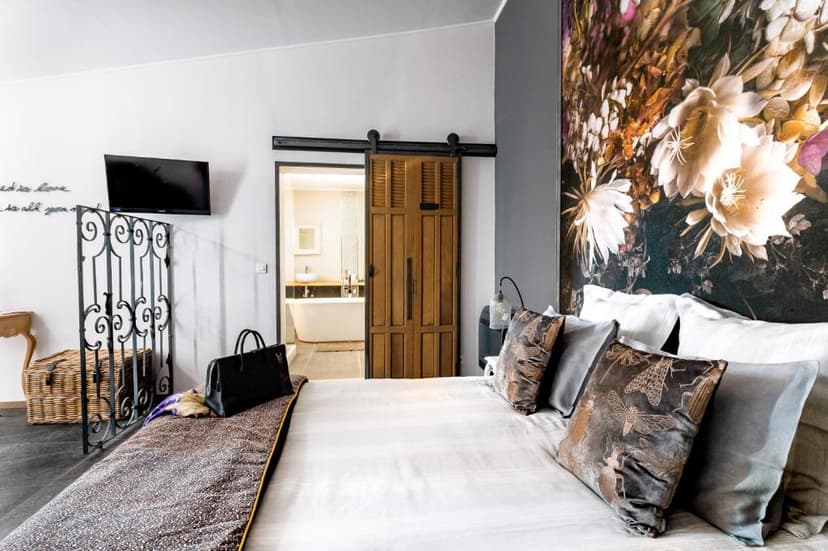 Bedroom with large floral mural, barn door to bathroom, and decorative pillows.