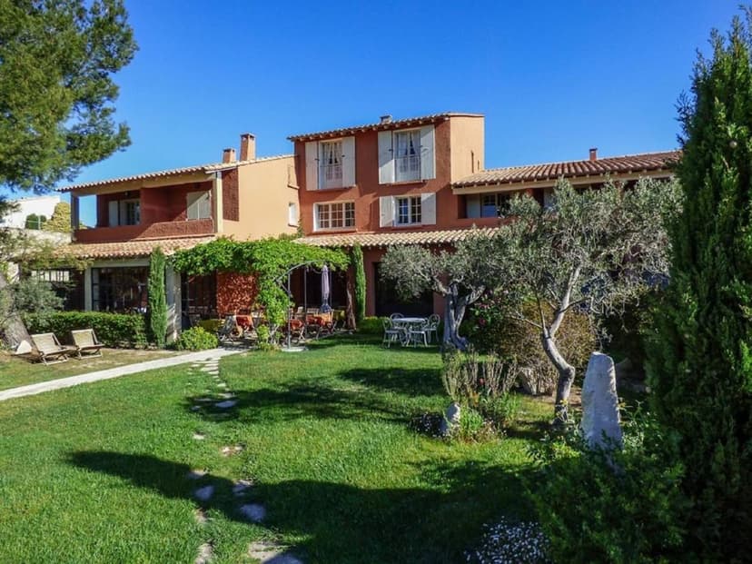 Terracotta building with garden, olive trees, and lawn in Castillon-Des-Baux.